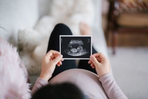 Pregnant woman holding ultrasound scan image